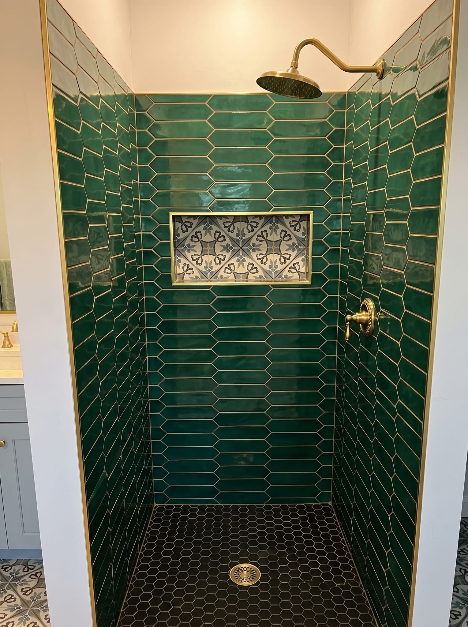 Bold emerald elongated picket tile shower, brushed gold rain-head, decorative encaustic niche, black hex floor — Mt Pleasant SC