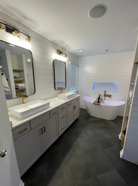 Modern master bath with double vessel-sink vanity, gold hardware, arched mirrors and freestanding oval soaking tub — James Island SC
