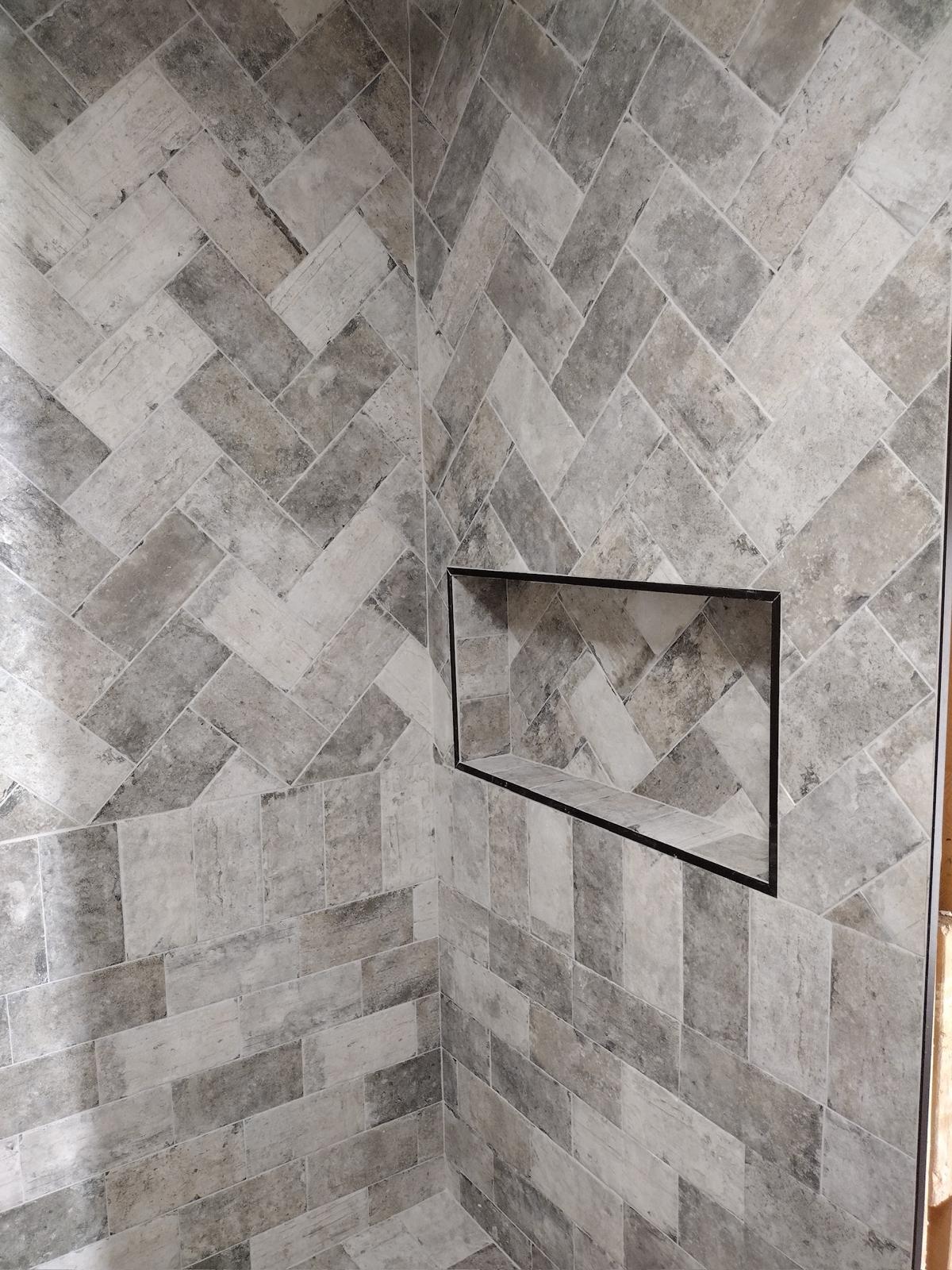 Gray stone-look full herringbone tile shower with built-in niche and frameless glass entry — Goose Creek SC
