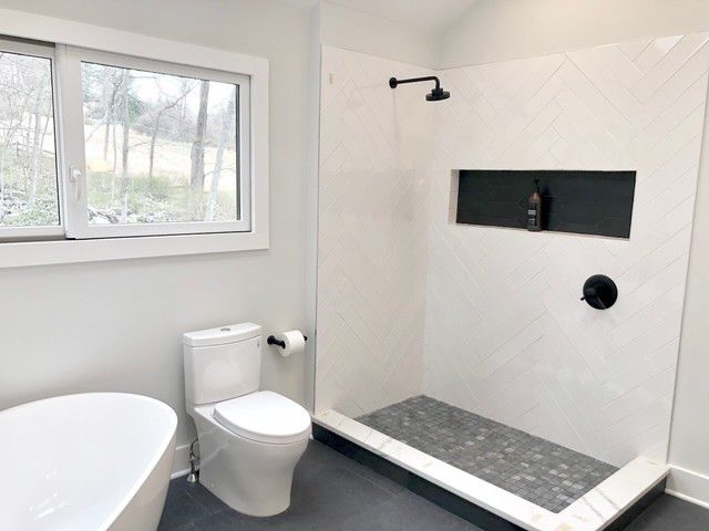 After: white herringbone walk-in shower with matte black fixtures and freestanding soaking tub — West Ashley SC